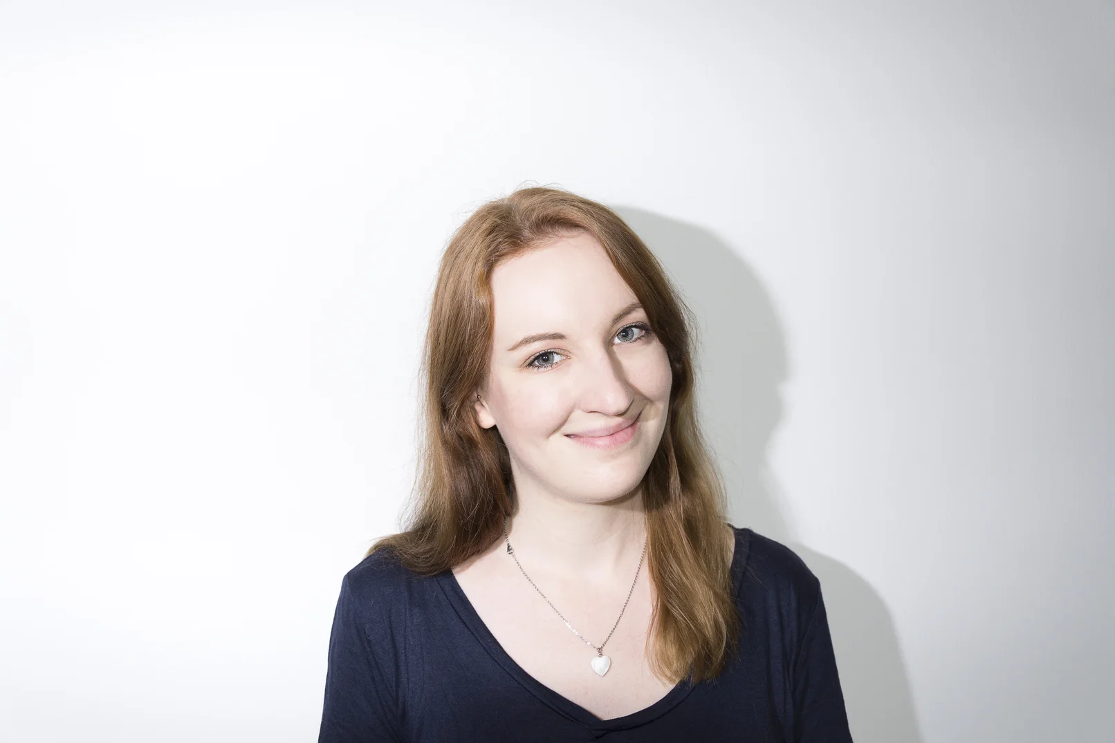 Frau vor weißem Hintergrund, die freundlich in die Kamera guckt