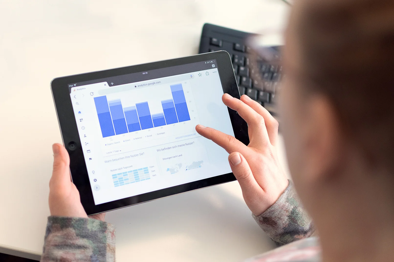 Person zeigt ein Balkendiagramm auf einem Ipad