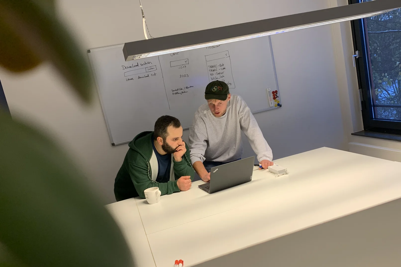 Zwei Männer schauen gemeinsam auf einen Laptop und diskutieren