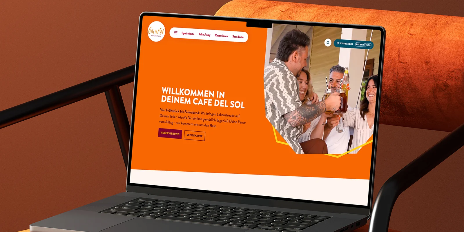Laptop auf einem orangefarbenen Stuhl mit geöffneter Cafe del Sol Website